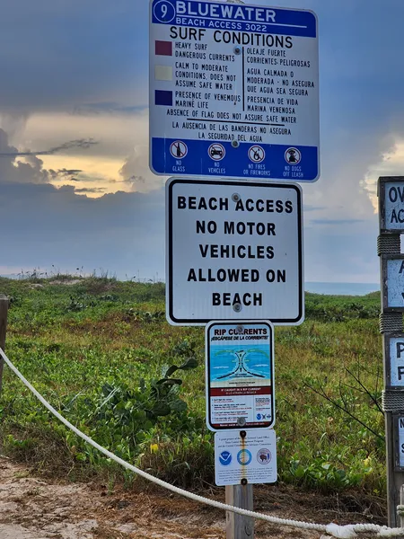 The Access 9 surf-conditions sign explaining the warning flag colors, above a No Motor Vehicles sign and a rip current sign.