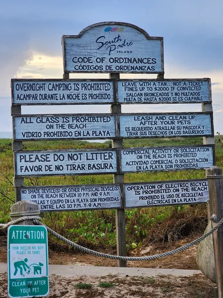 The town's Code of Ordinances board in English and Spanish: no overnight camping, no glass, no litter, leash and clean up after pets, no commercial activity, no electric bicycles on the beach.