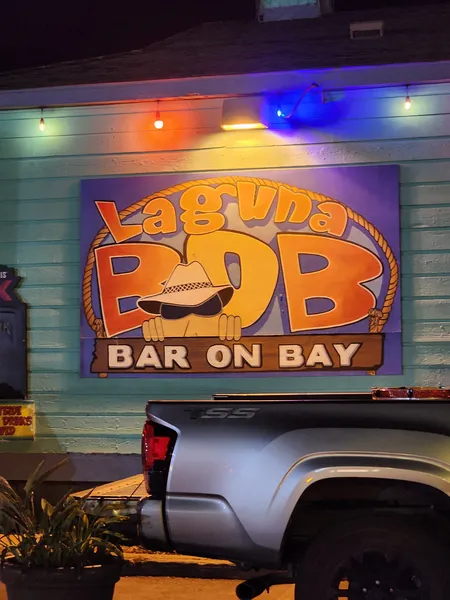 The Laguna BOB Bar on Bay sign on a teal wall, lit with colored lights, above a parked pickup.