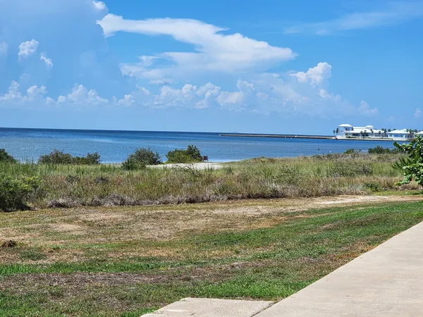 Blue Laguna Madre water beyond grasses and a paved path near the Convention Centre.