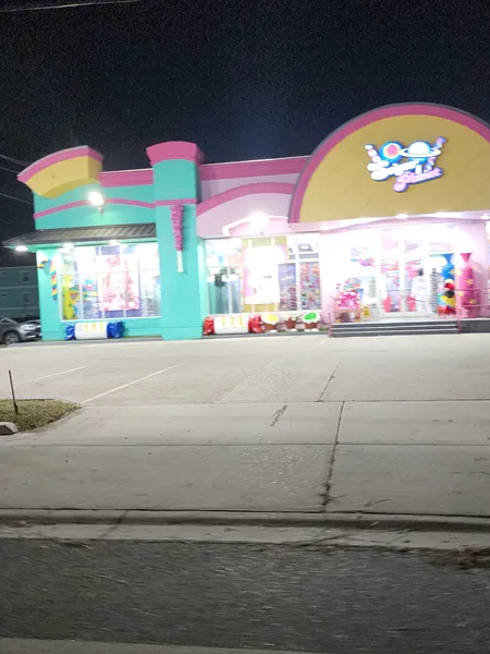 The pink-and-teal Sugar Planet candy store lit up at night.