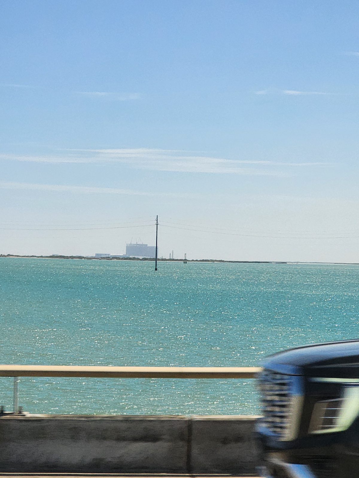 Turquoise bay water and a distant shoreline seen from the causeway.