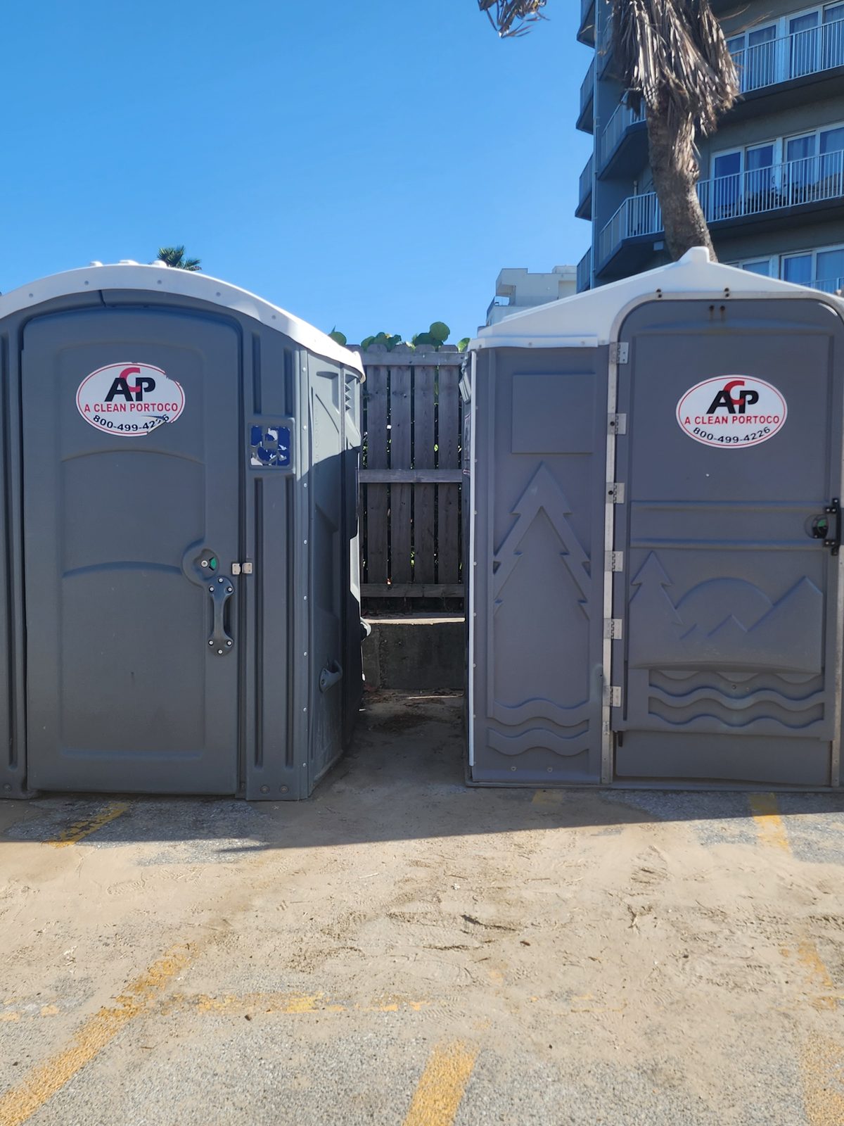 Two portable restrooms stand near a beach access.