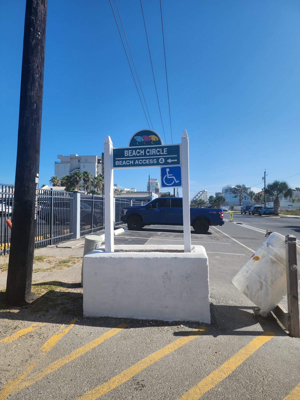 A sign points to Beach Circle Beach Access 4 beside a parking area.