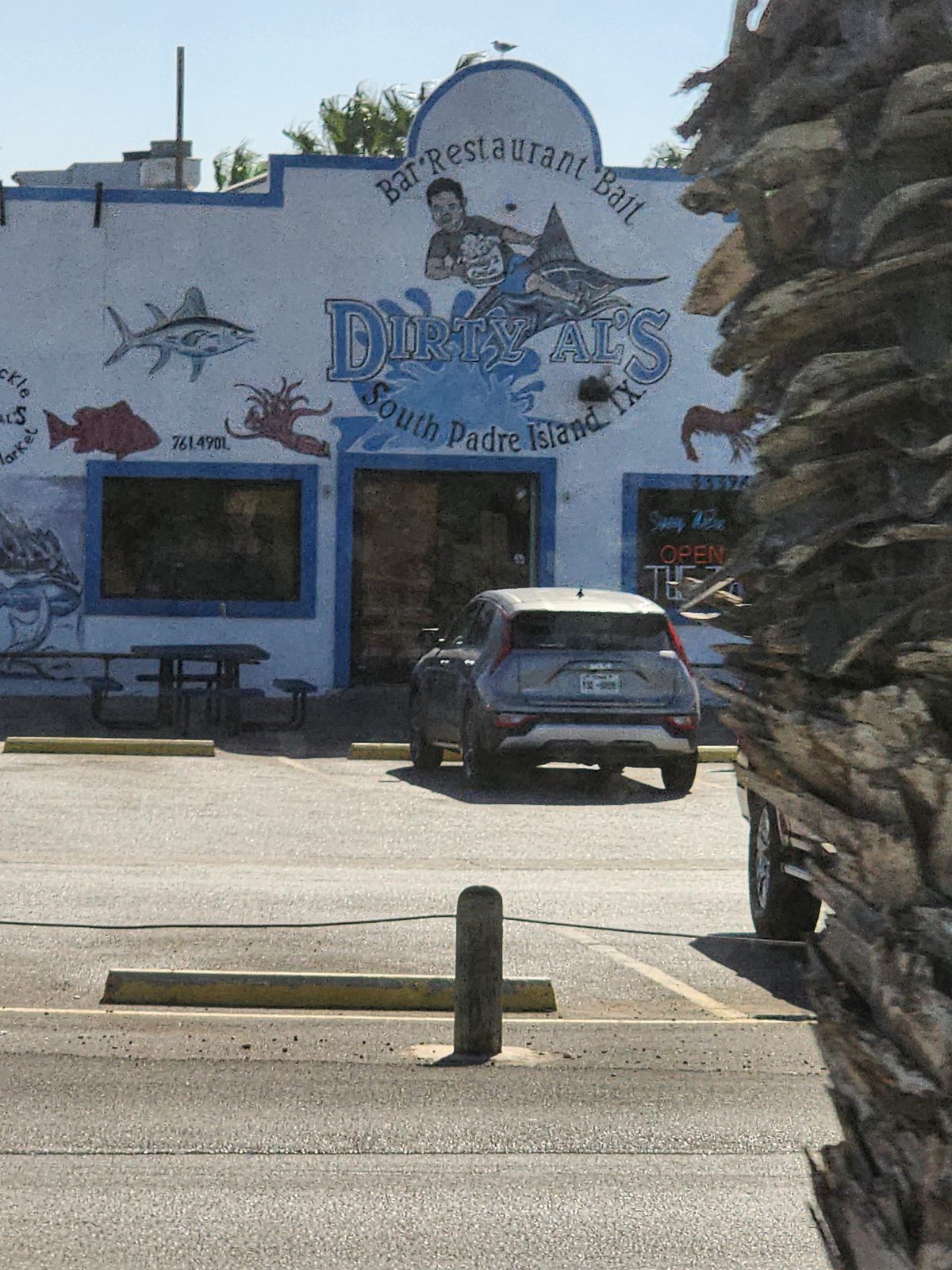 Dirty Al's restaurant storefront with marine-life mural artwork and parked vehicles.