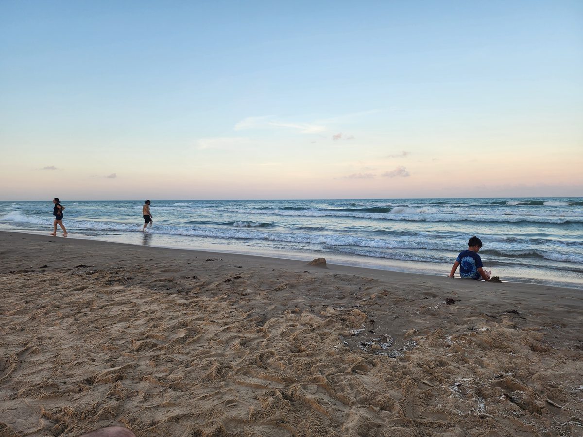 Beachgoers near the shoreline in the last light of the day.
