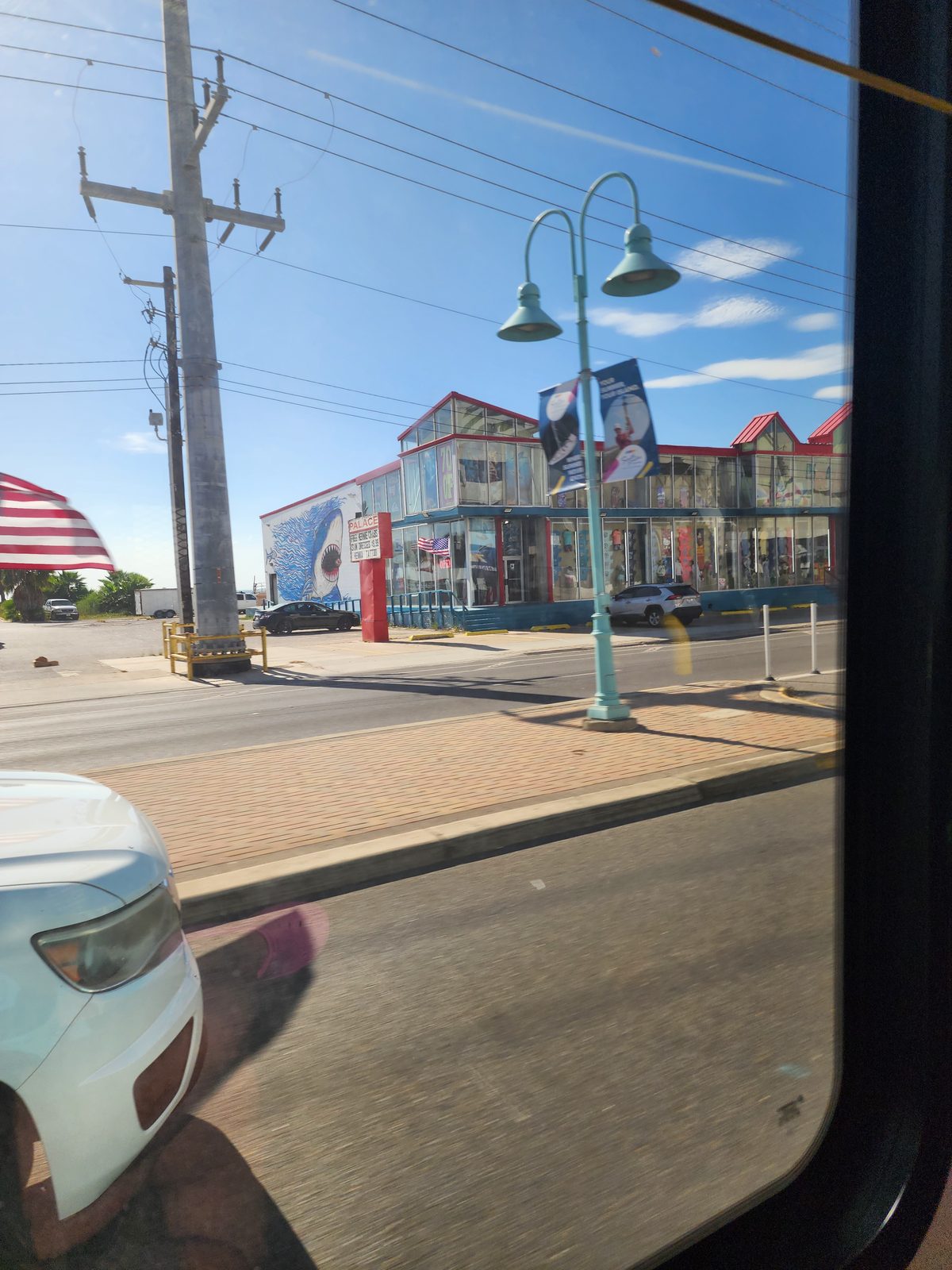 Colorful multi-story shop building across a boulevard, seen through a vehicle window.