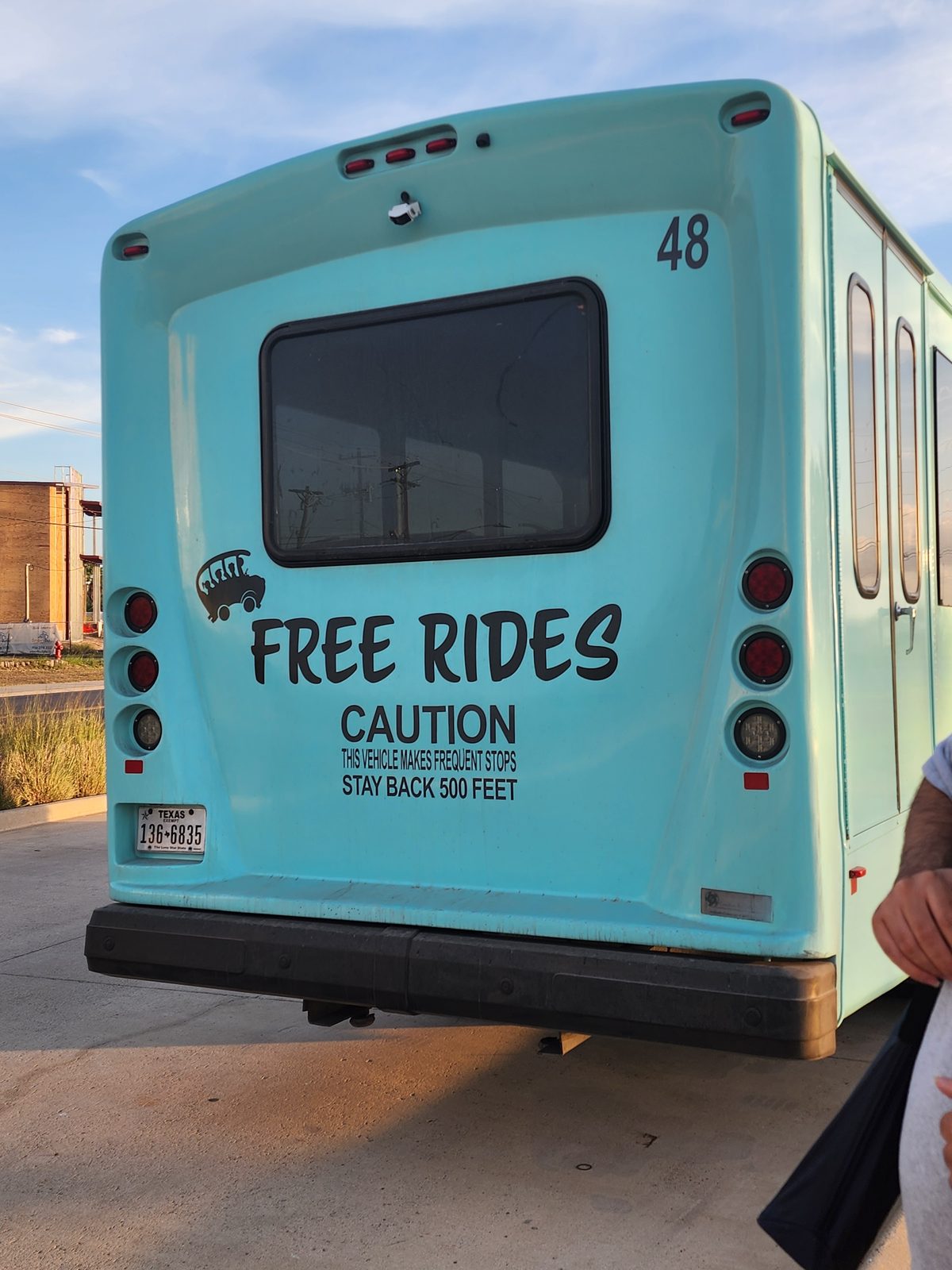 Rear view of a mint-green Island Metro bus numbered 48, with Free Rides lettering and a caution notice about frequent stops.