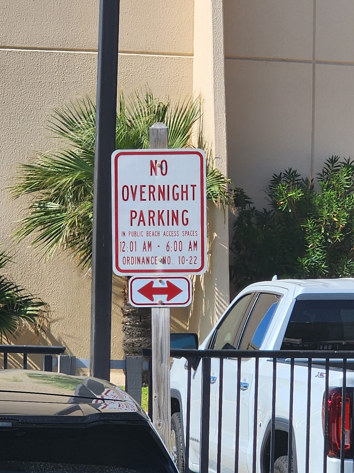 A no overnight parking sign stands beside parked vehicles.
