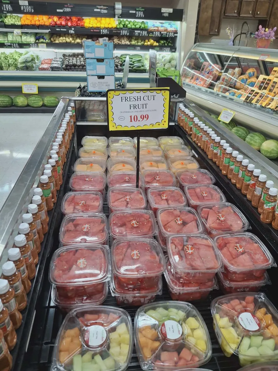 A refrigerated case of fresh-cut watermelon, melon and fruit cups under a "Fresh Cut Fruit" sign
