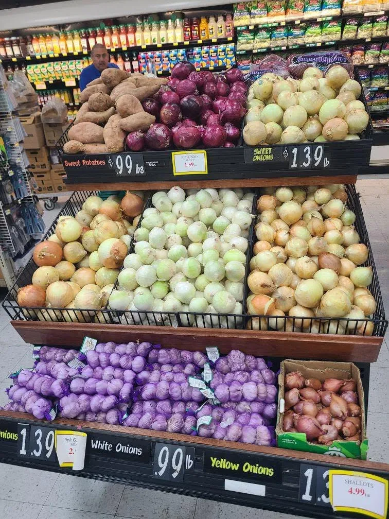 Bins of sweet potatoes, red, white and yellow onions, garlic and shallots