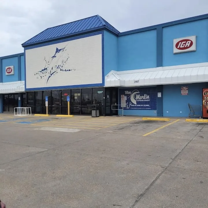 The Blue Marlin Supermarket building: a blue storefront with a white marlin mural, IGA signs and the Blue Marlin sign by the door