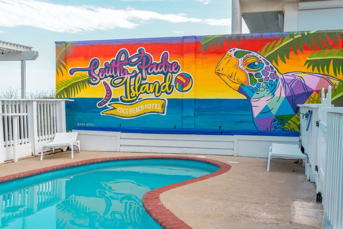 The outdoor pool in front of a bright South Padre Island mural with a sea turtle