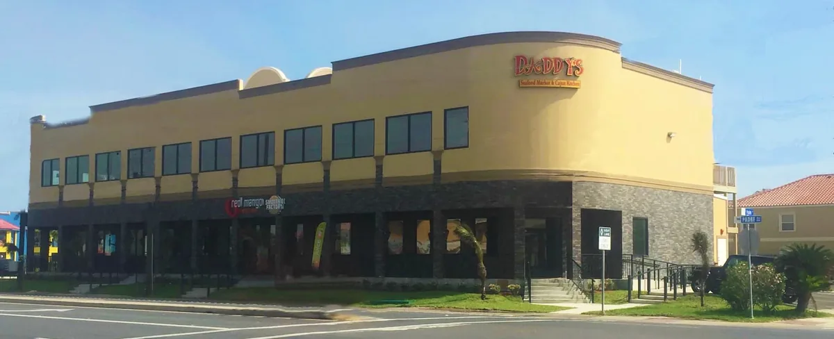 The two-story building on Padre Boulevard with the Daddy's Seafood Market & Cajun Kitchen sign on its corner