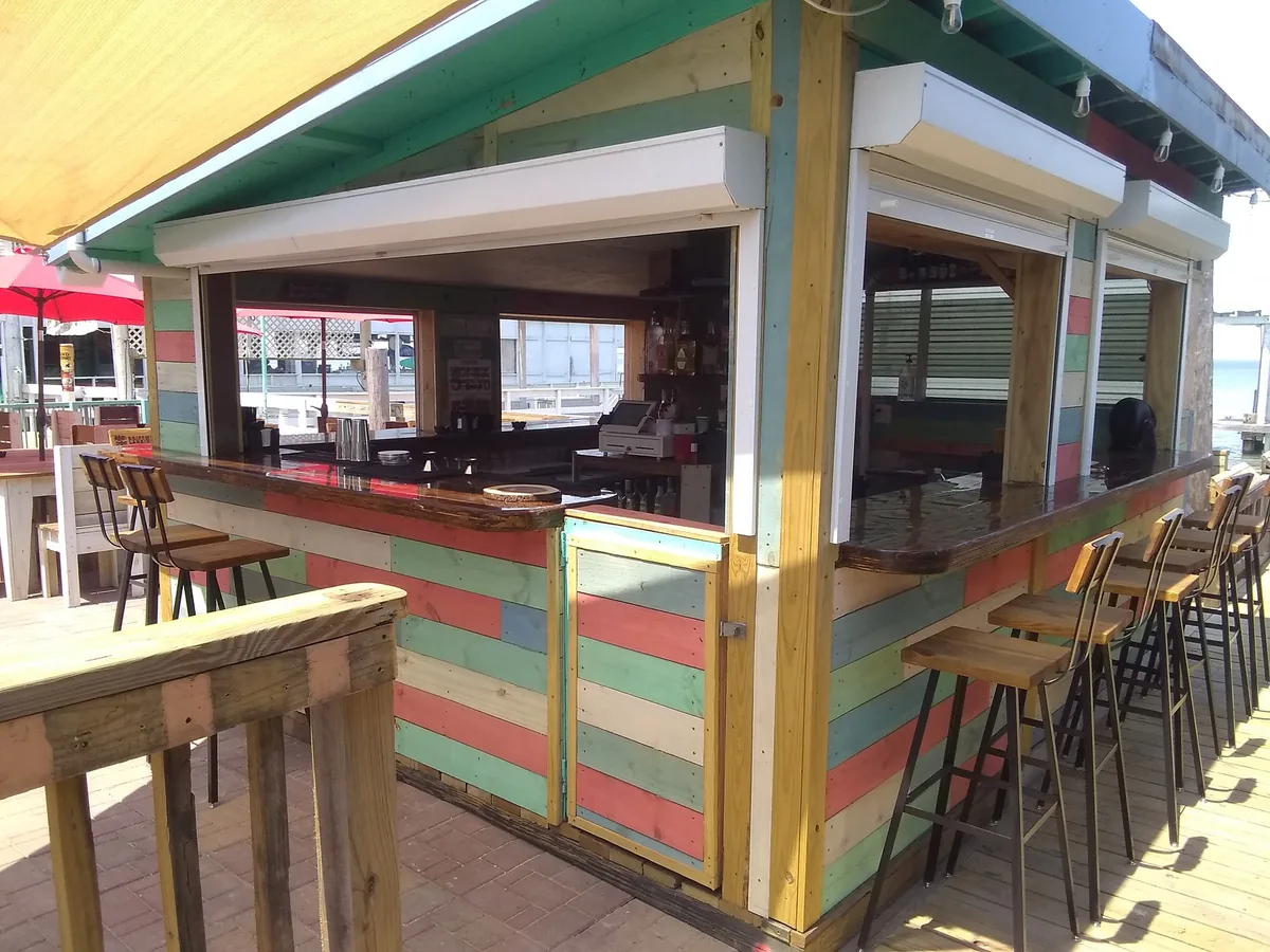 The open-air bar with striped pastel walls and a row of bar stools