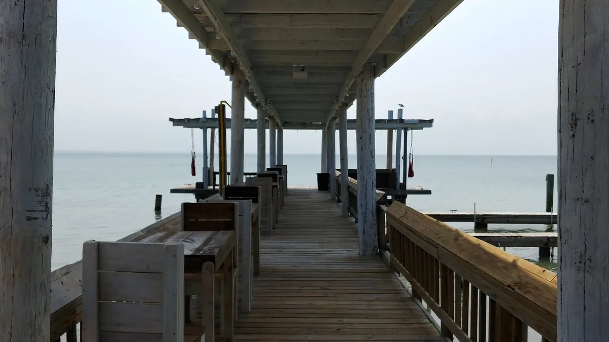 A covered pier with benches leading out over the bay