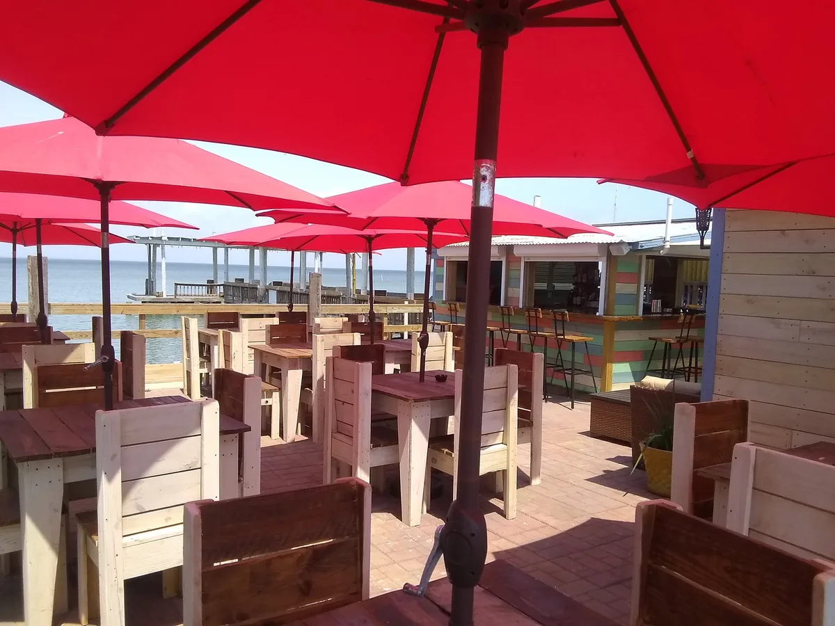 The outdoor deck with red umbrellas over wooden tables and chairs by the water