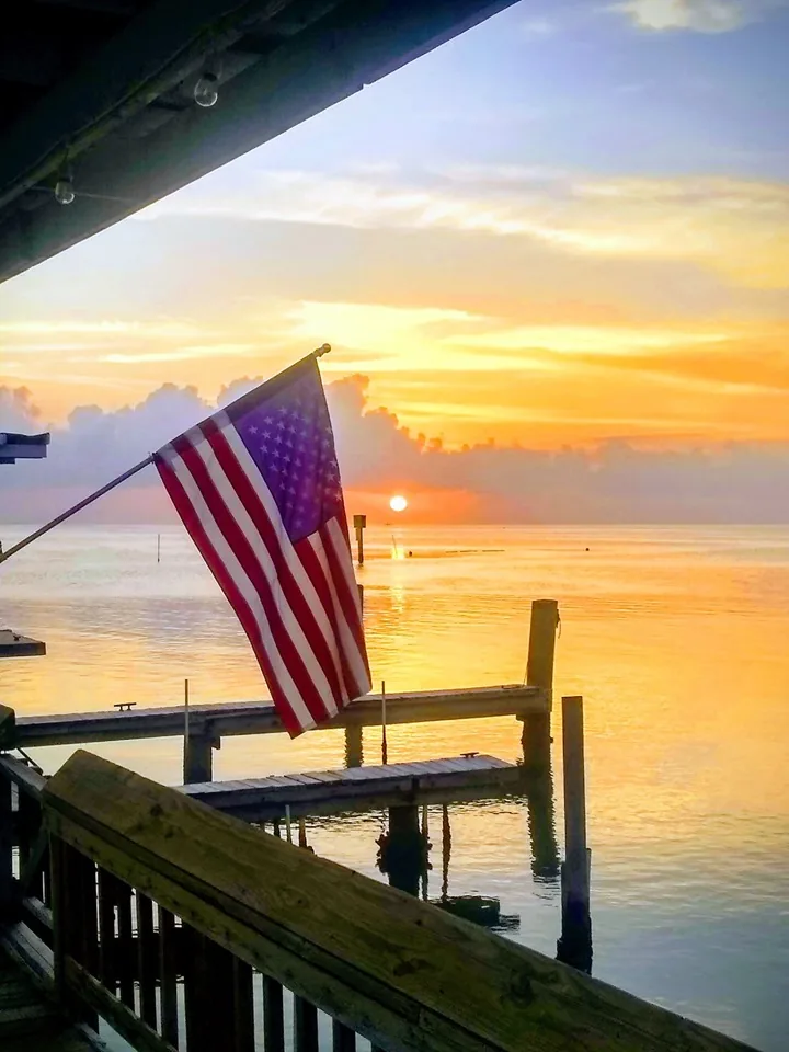 An American flag on the rail at sunset over the bay