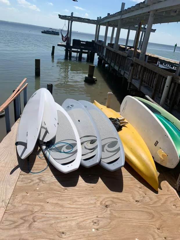 Paddleboards stacked on the dock beside the water