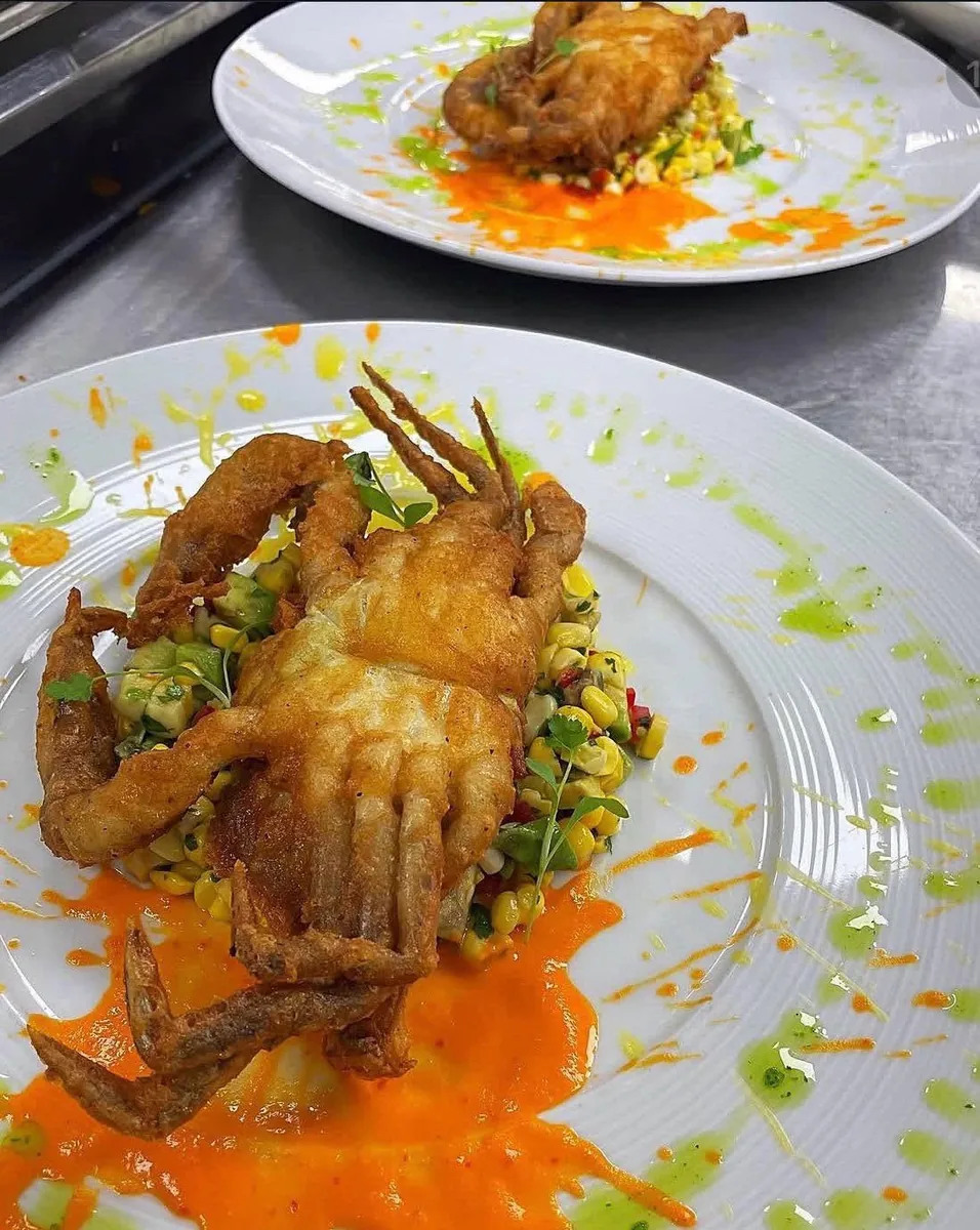 A fried soft-shell crab on a corn salad with orange and green sauces