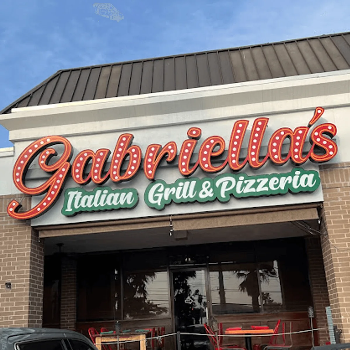 The Gabriella's Italian Grill & Pizzeria sign in marquee-bulb letters above the entrance and patio seating