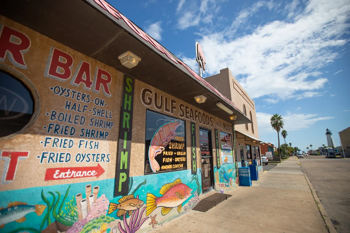 The side of the building painted with sea life and the words Oysters on the Half Shell, Boiled Shrimp, Fried Fish and Fried Oysters by the entrance