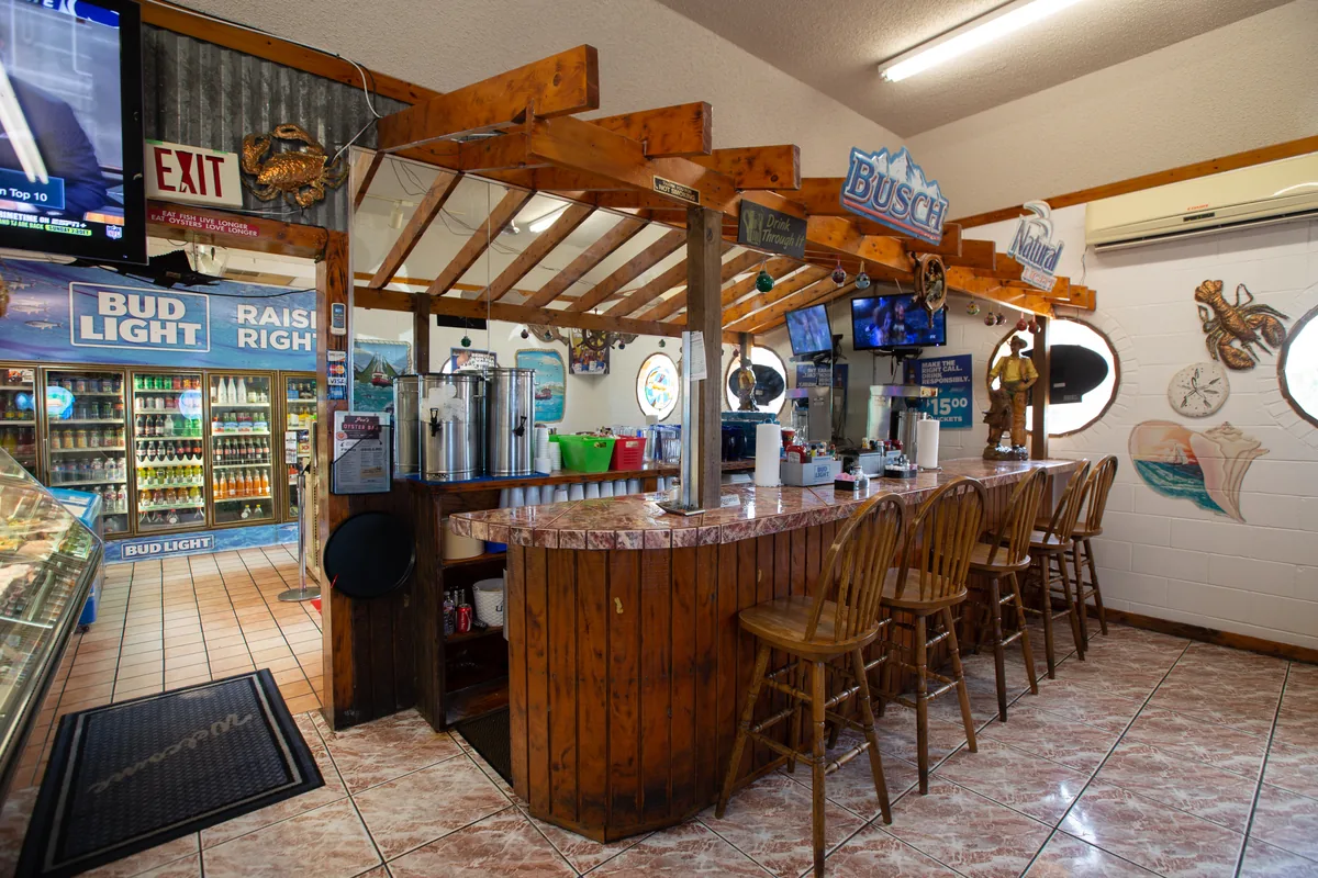 The oyster bar: a wooden bar with stools under a wooden trellis, with coolers and seafood decorations