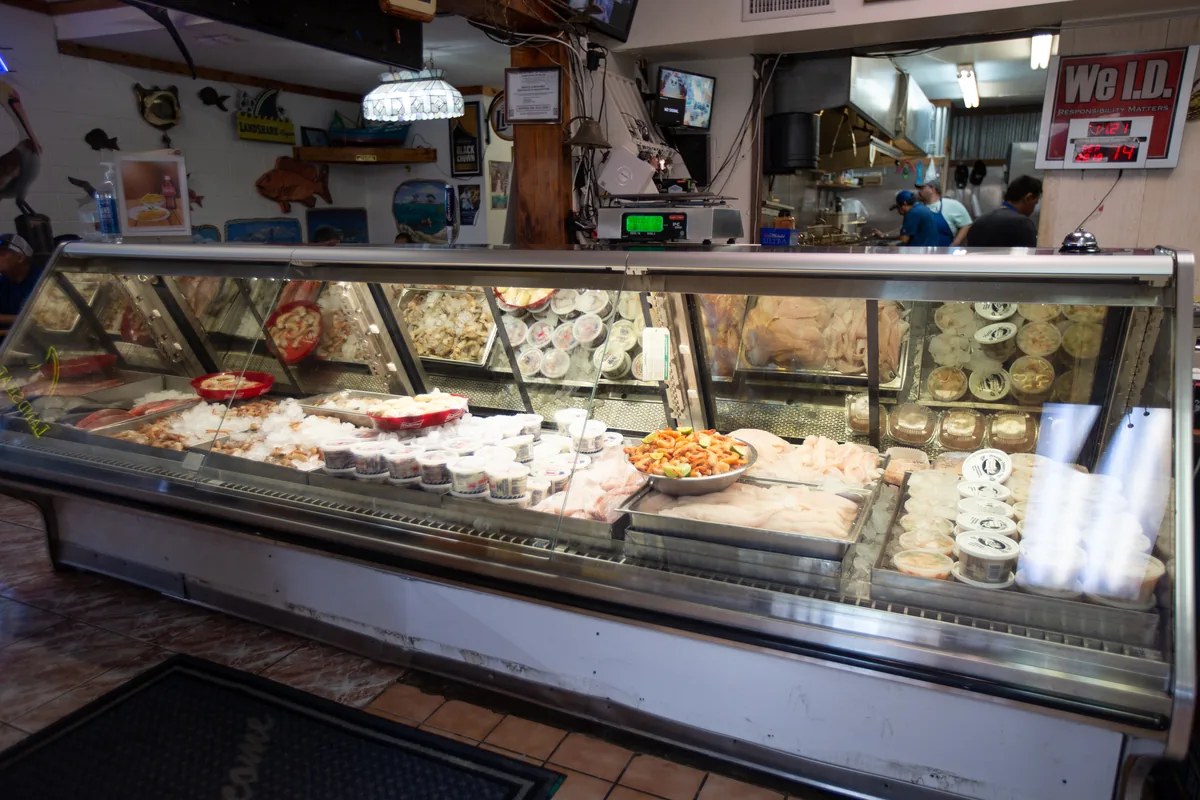 The long glass seafood counter of Gulf Seafood Market, filled with fish, shrimp and containers of seafood