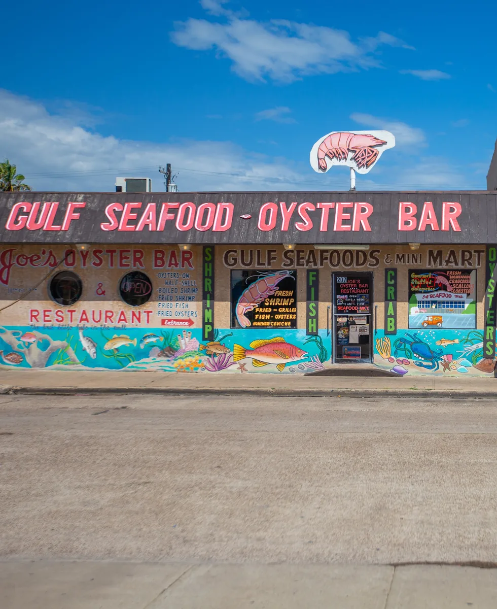 The Gulf Seafood - Oyster Bar sign on top of the painted building, with a shrimp on the pole