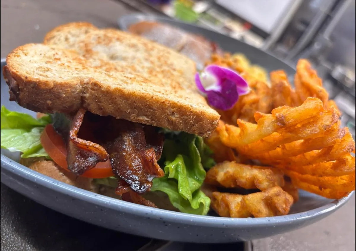 A BLT on toasted wheat bread with crisp bacon, lettuce and tomato, served with waffle fries