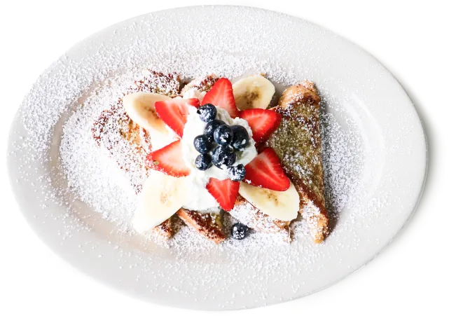 French toast topped with whipped cream, strawberries, banana slices and blueberries, dusted with powdered sugar