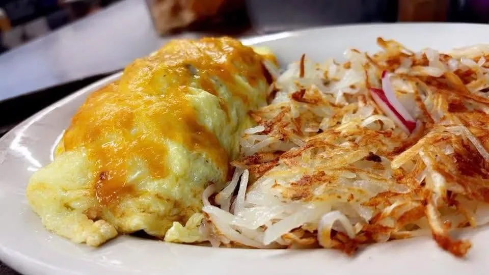 An omelet under melted cheddar with crispy hash browns