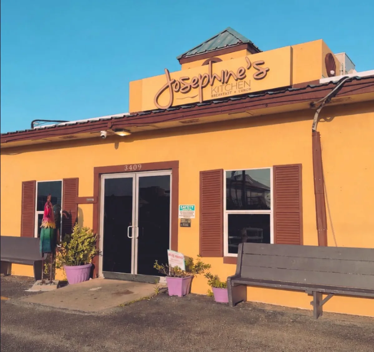 The yellow Josephine's Kitchen building at 3409 with its sign, brown shutters, benches and flower pots