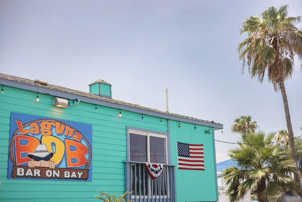 The teal Laguna BOB building with its Bar On Bay sign, an American flag and palm trees