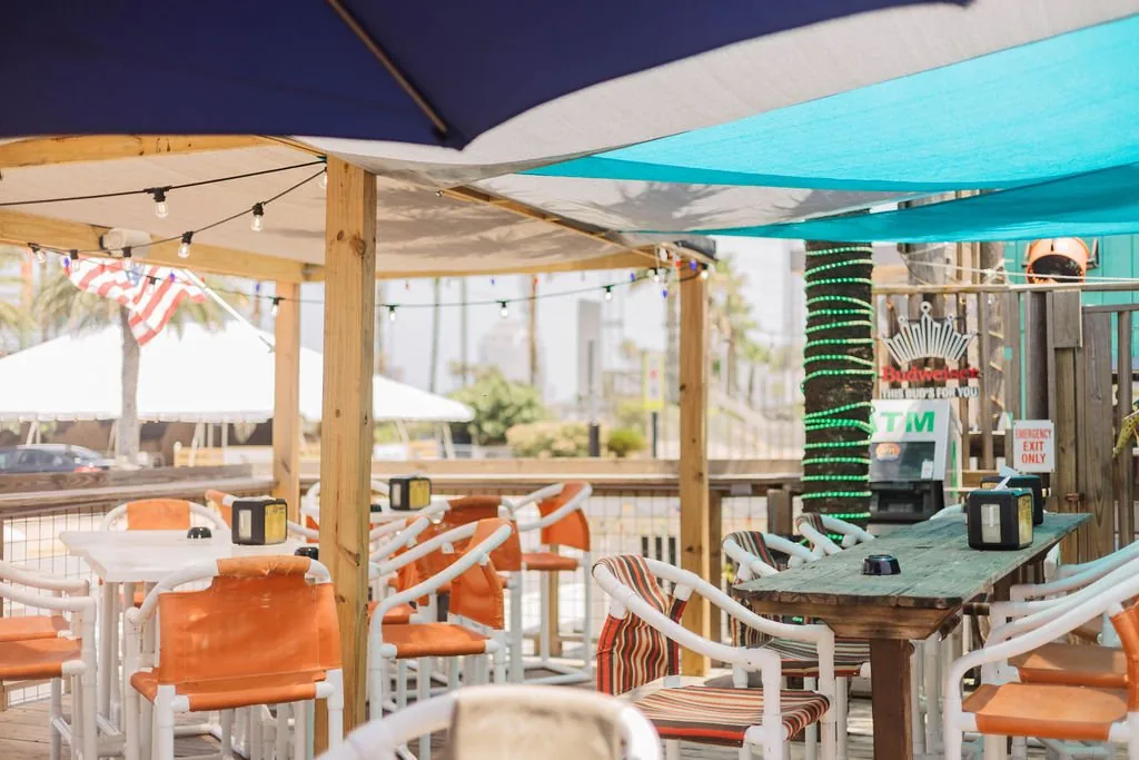 Covered deck seating with orange chairs, string lights and shade sails