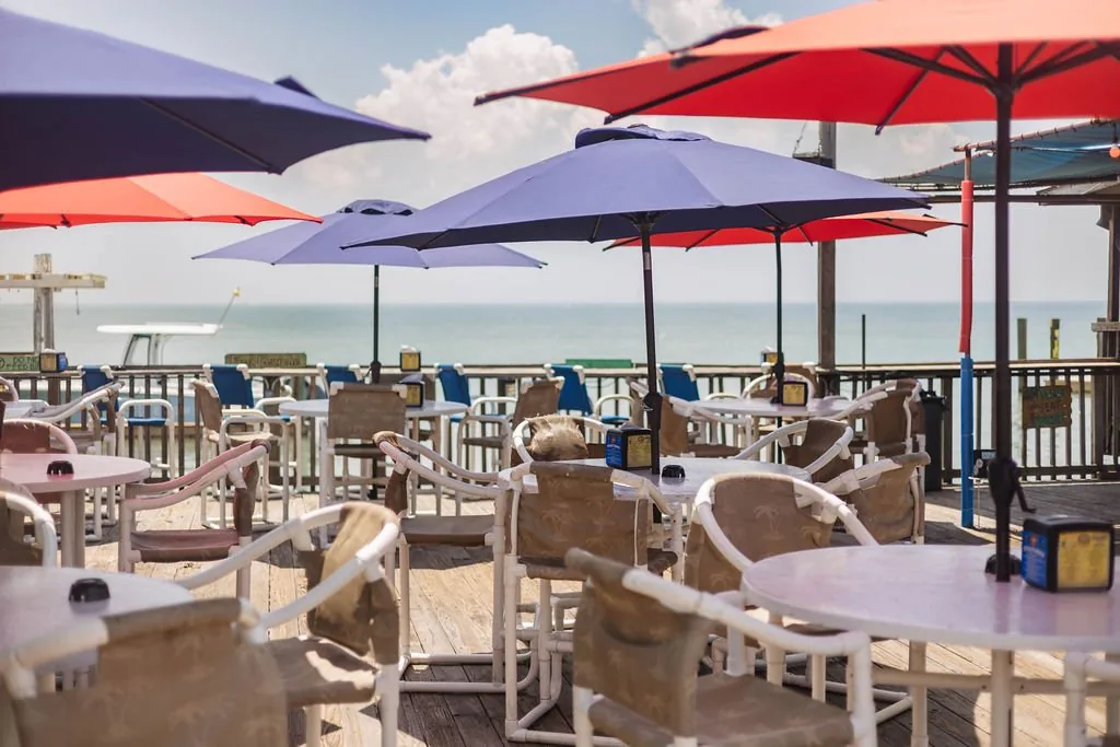 The open-air deck with purple and red umbrellas over tables and chairs, looking out over the Laguna Madre