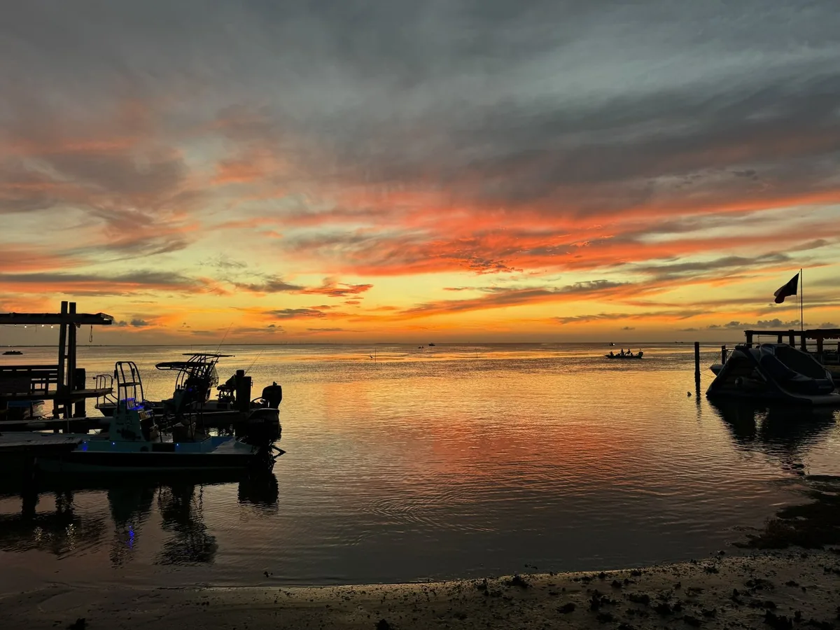 An orange and pink sunset over the Laguna Madre, with fishing boats at the docks
