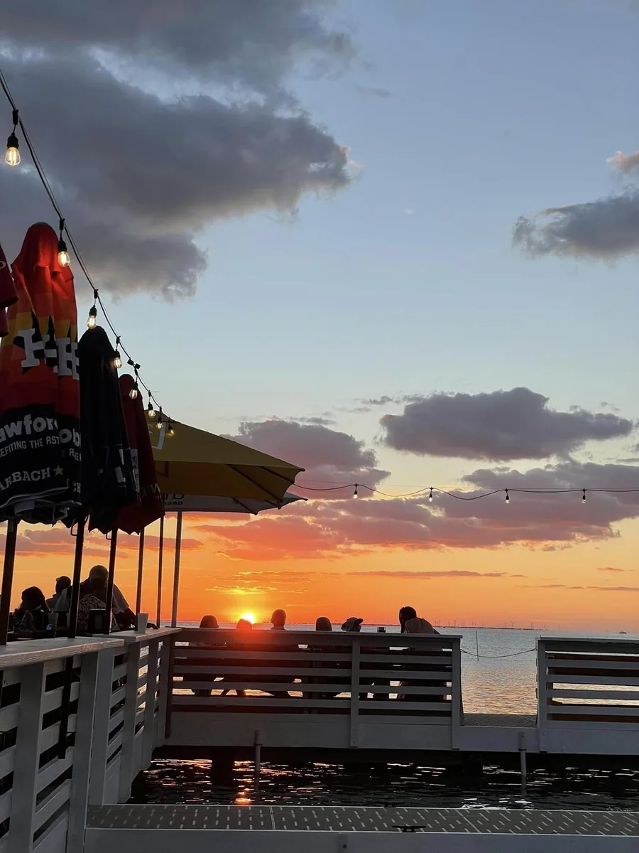 Umbrellas and the deck rail as the sun sets over the bay