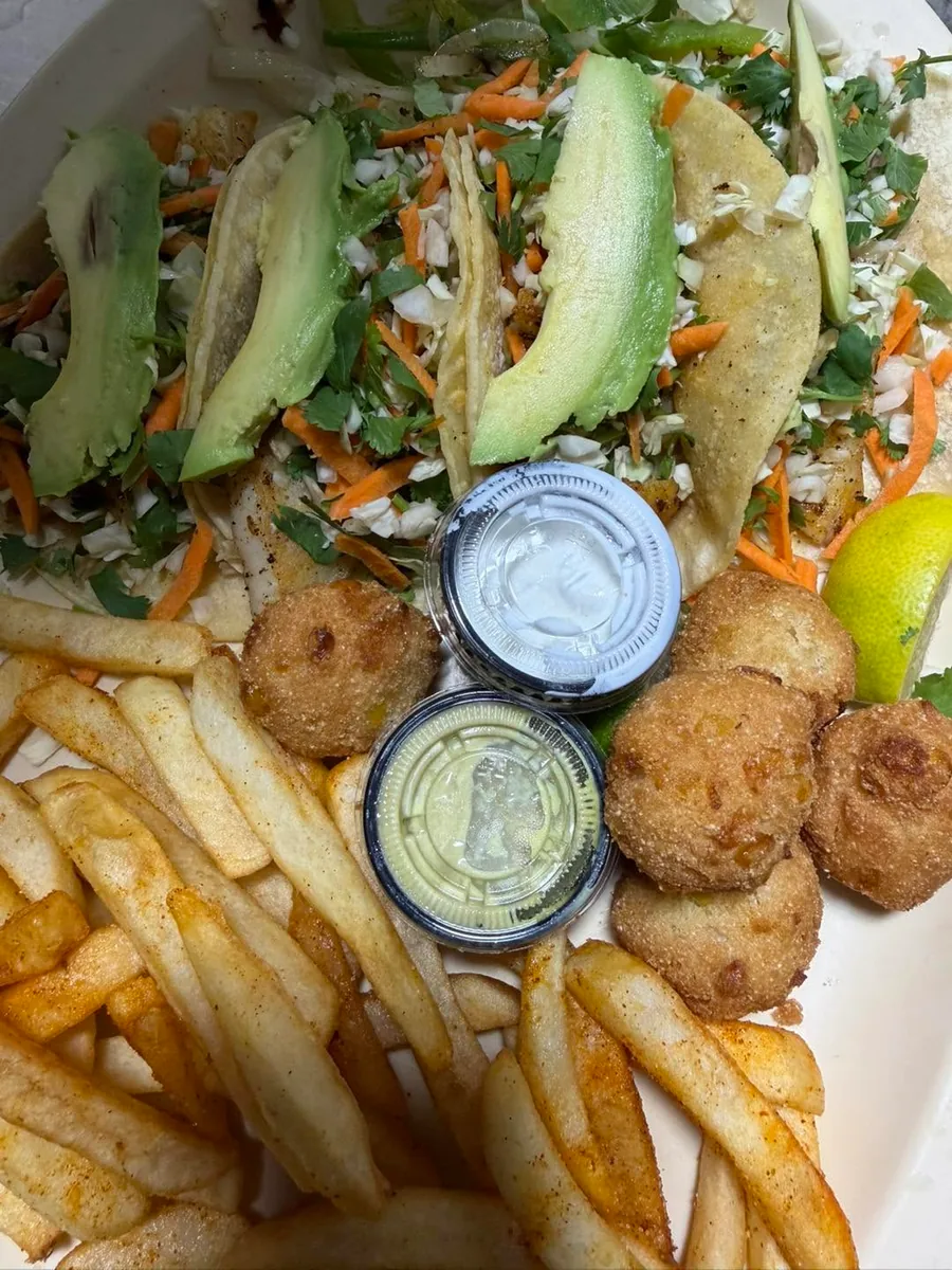 Fish tacos with slaw and avocado, served with fries, hush puppies and dipping sauces