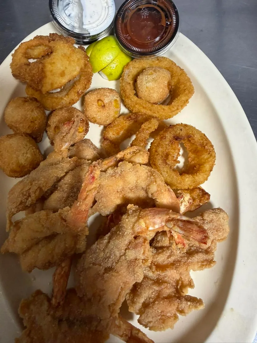 Fried shrimp and fish with onion rings and hush puppies on an oval plate