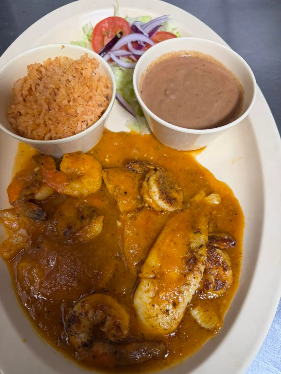 Shrimp and fish in an orange sauce with rice, beans and salad