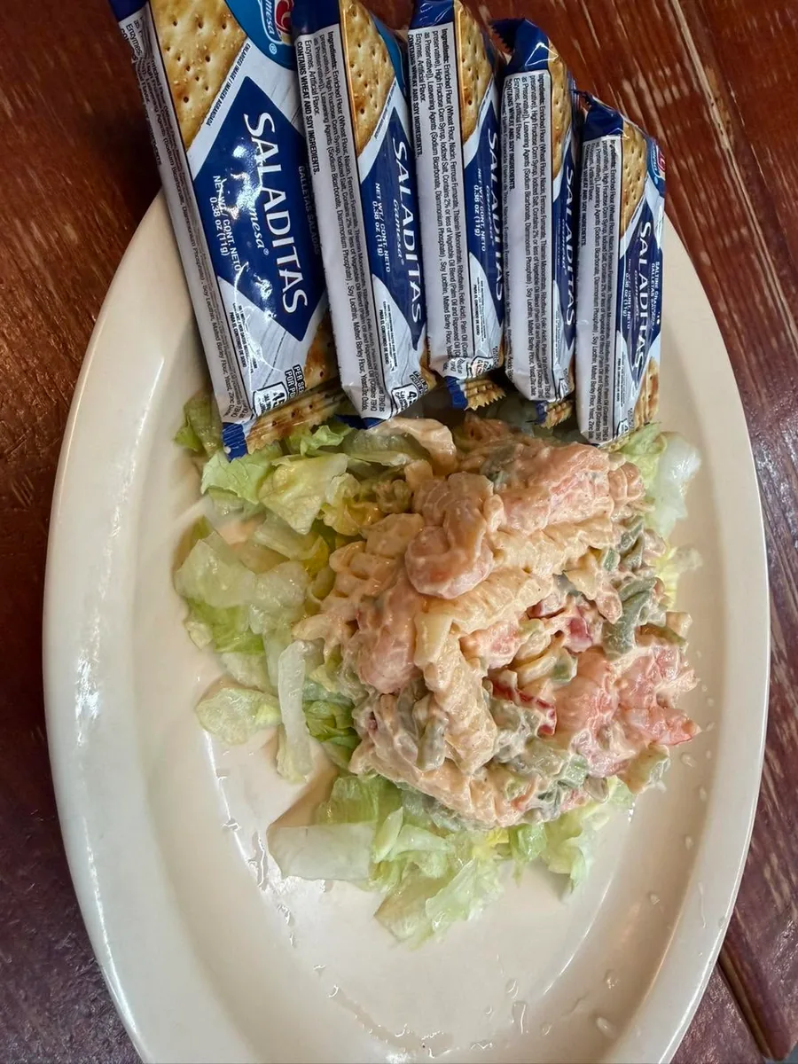A creamy shrimp salad on lettuce with packs of saltine crackers