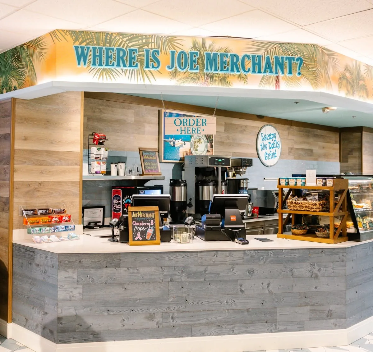 The Joe Merchant's Coffee & Provisions counter under a "Where is Joe Merchant?" mural, with coffee machines and pastries