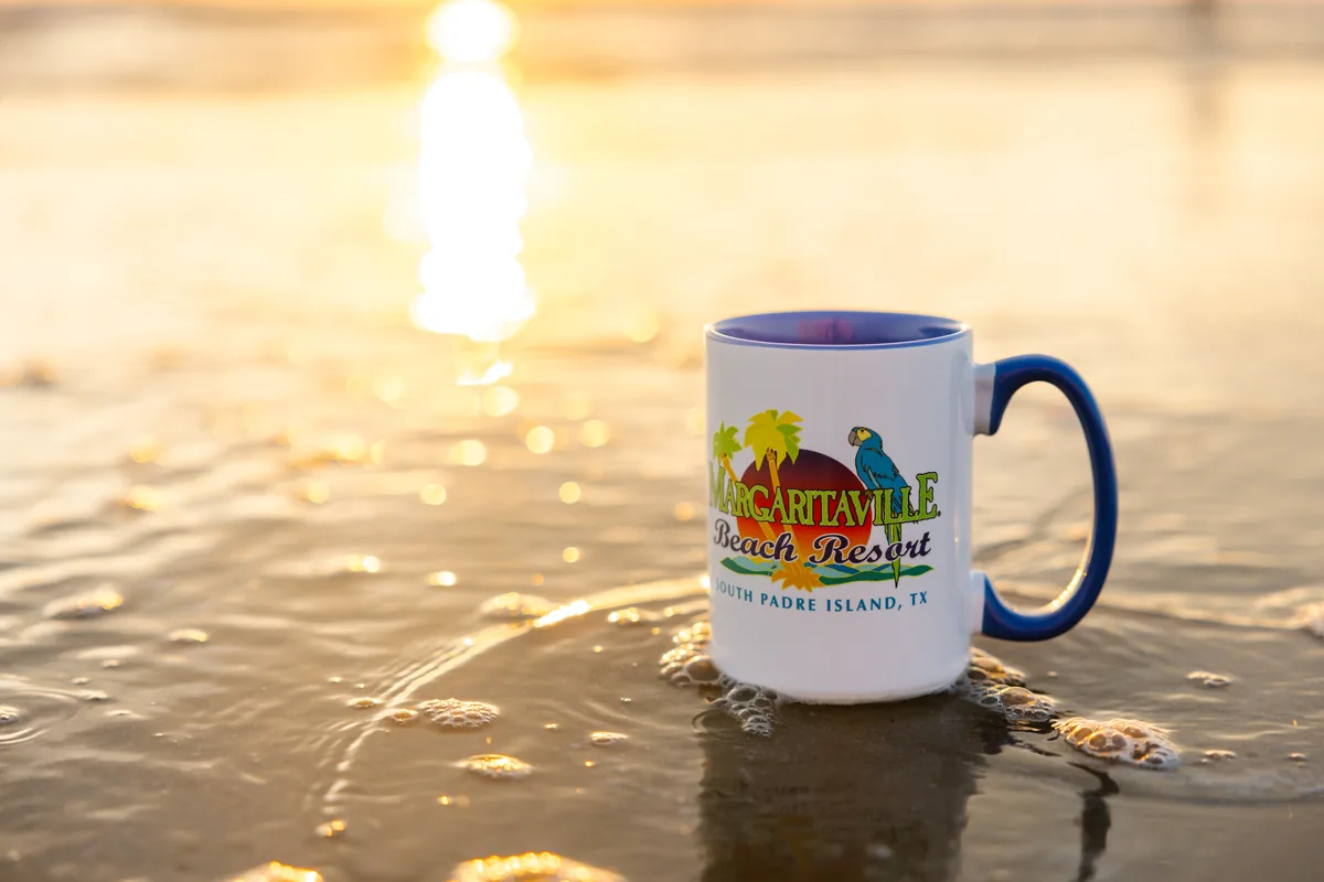 A Margaritaville Beach Resort South Padre Island coffee mug in the surf at sunrise
