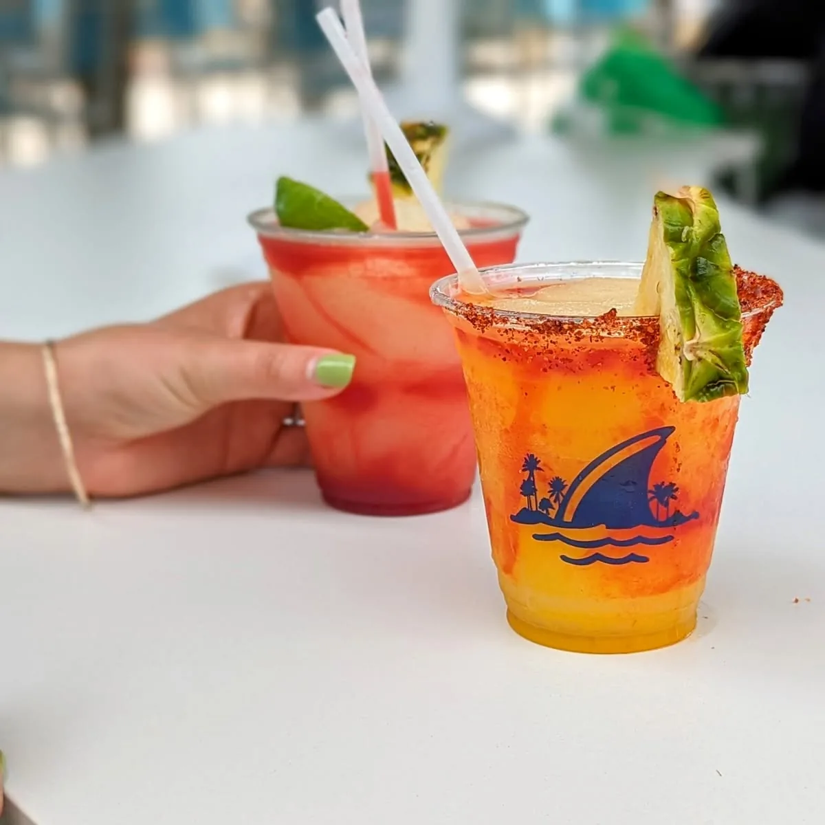 Two frozen cocktails at the Salty Rim: a red one with lime and an orange one with a chili-salt rim and a pineapple wedge