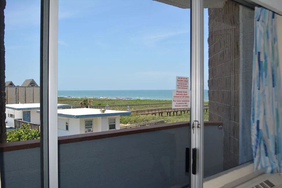 The view from a room balcony over low buildings and the dunes to the Gulf