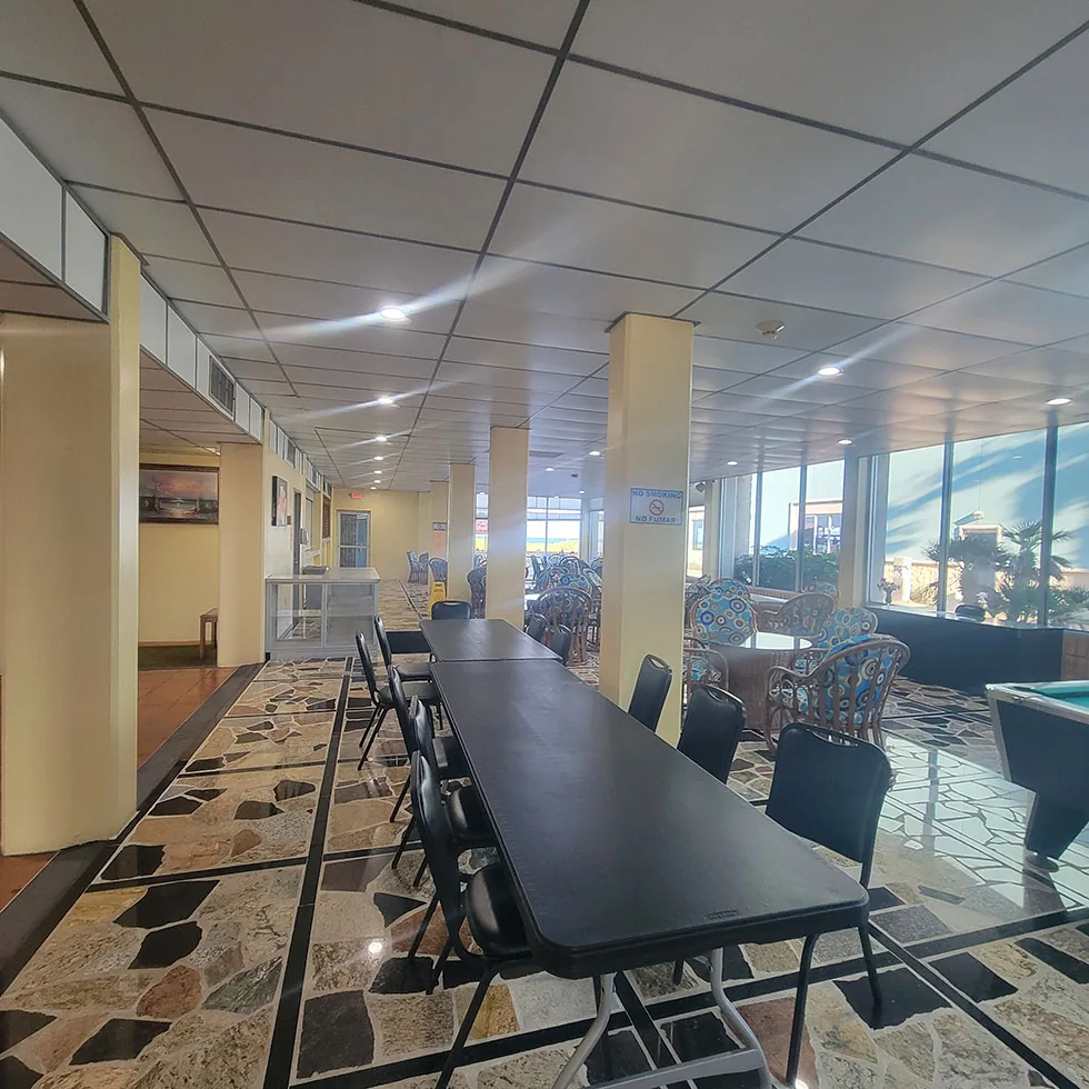 The lobby with long tables, patterned stone floor and windows toward the Gulf, and a pool table
