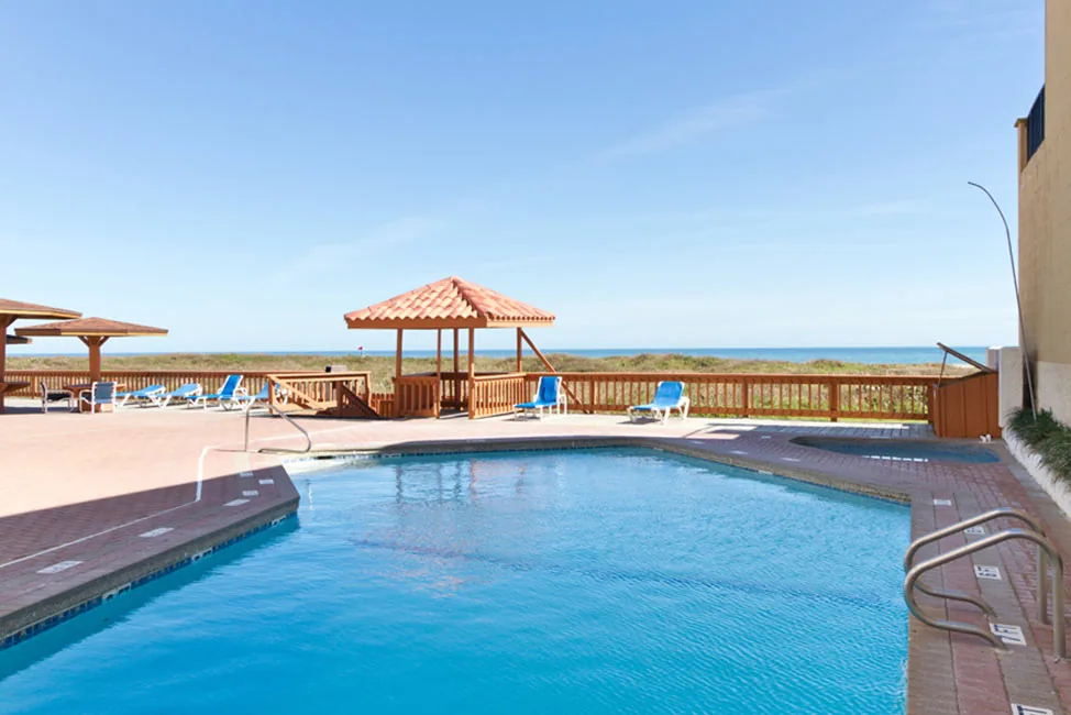 The pool deck with a wooden gazebo and loungers, looking out over the dunes to the Gulf