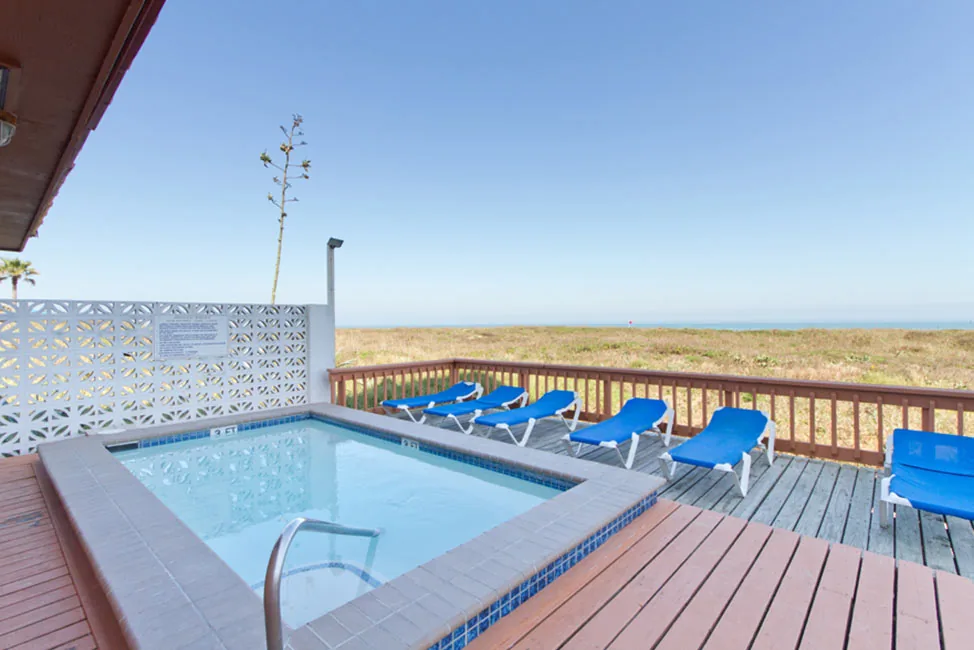 A small square pool on the wooden deck, with blue loungers and the Gulf beyond the dunes