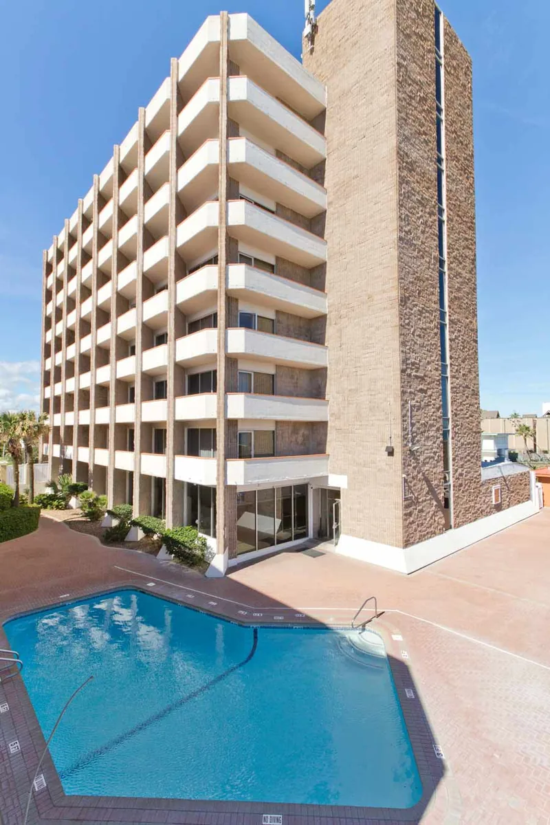 The Padre South tower of balconies above the pool deck, under a blue sky